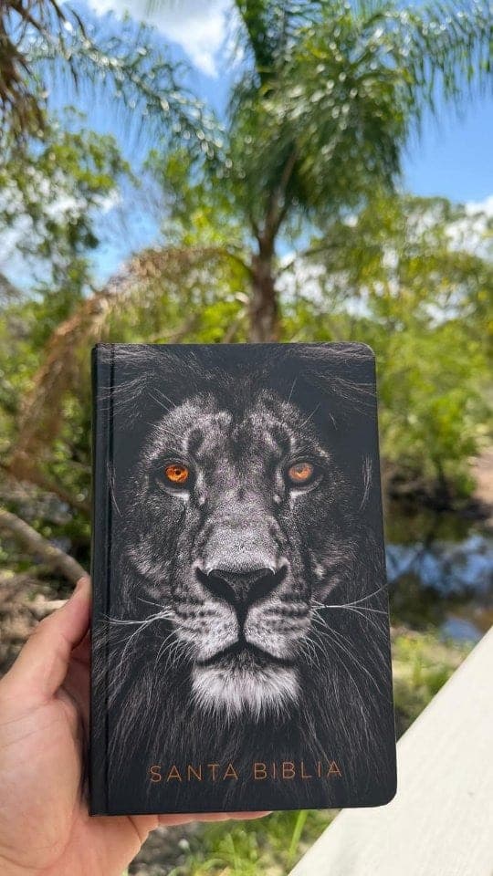 Santa Biblia con un león en escala de grises y ojos naranja en la portada